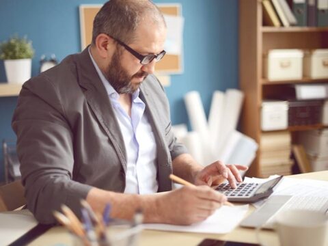 Hombre sentado en un escritorio con una calculadora