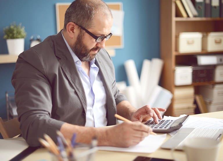 A Man Sitting at a Desk with a Calculator