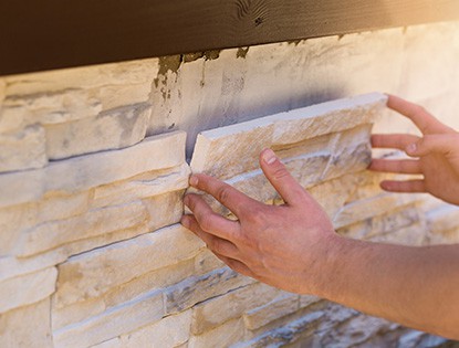 Primer plano de manos instalando piedra decorativa en una edificación