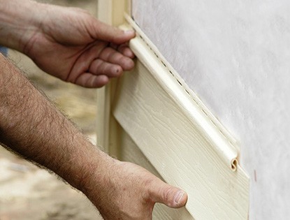 Primer plano de dos manos instalando una pieza de revestimiento de vinilo