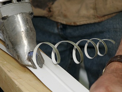 Manos cortando aluminio con una herramienta eléctrica