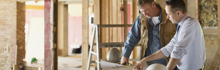 Male Architect and Foreman Discussing Blueprint at Construction Site