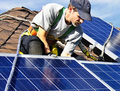 Hombre instalando paneles solares fotovoltaicos sobre un techo