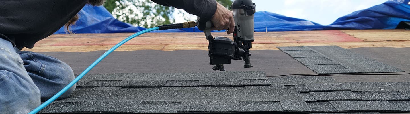 Instalador de techos utilizando una pistola de clavos para instalar tejas