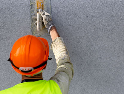 Worker Applying Stucco Finish With Hand Trowel