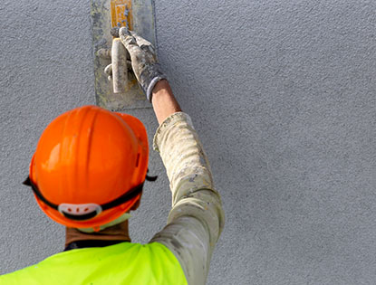 Trabajador aplicando acabado de estuco con una llana