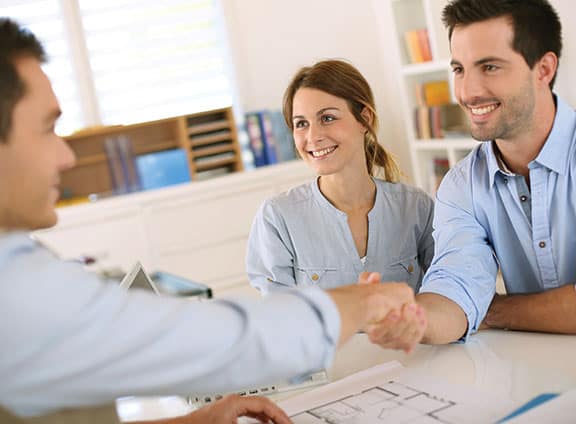 Couple Shaking Hands Over Blue Prints