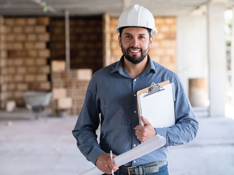 Trabajador de la construcción con casco protector y portapapeles, sosteniendo planos